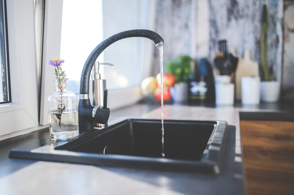 Tap water running from a black faucet in a black sink.